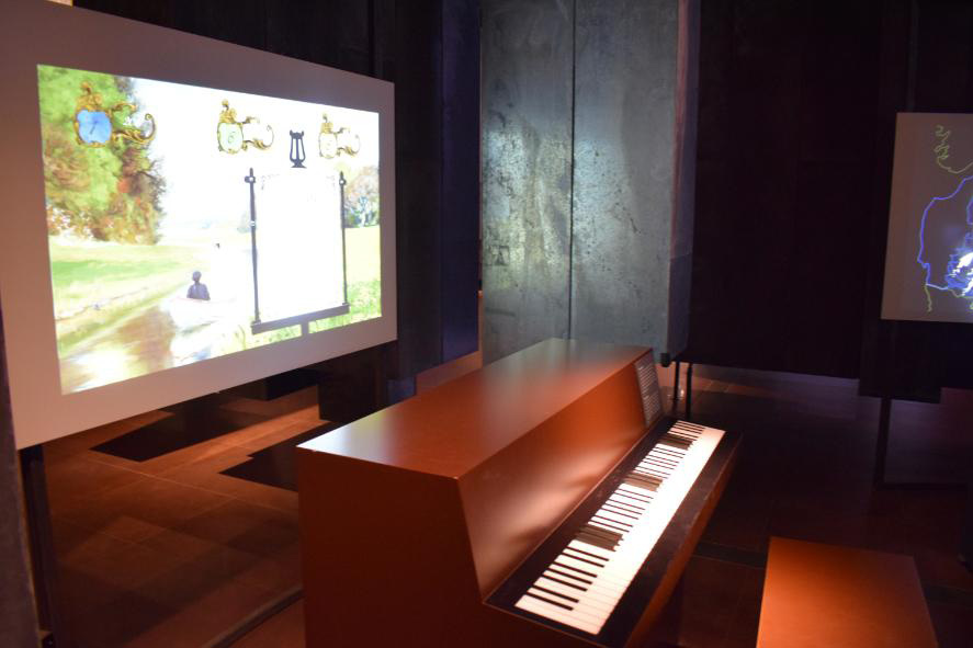 Museum Møntergården (à esquerda): piano e tela interativa da sala imersiva do Museu – Odense (Fyn).